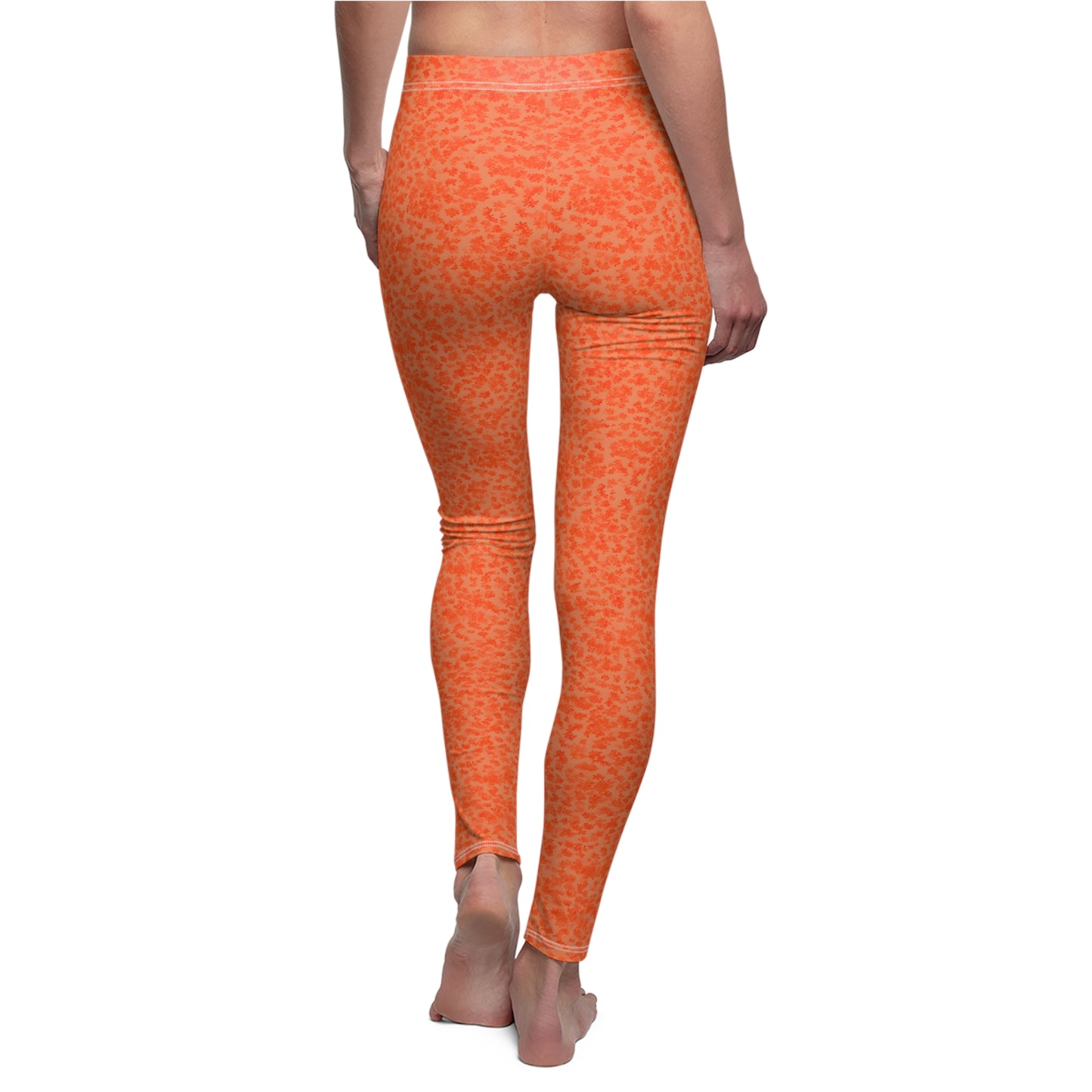 A pair of orange skinny fit leggings with a pattern, made from polyester and spandex fabric. Back view, on model.
